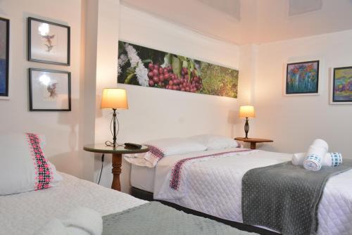 a room with two beds and two lamps and pictures on the wall at La Estancia Hotel Boutique in Salamina