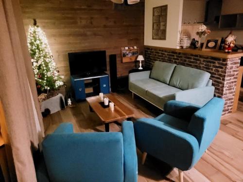 a living room with blue chairs and a couch and a christmas tree at Le Meublé MONESTOIS in Mennetou-sur-Cher
