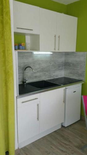 une cuisine avec des armoires blanches et un évier dans l'établissement Studio double cabine vu mer, au Grau-du-Roi