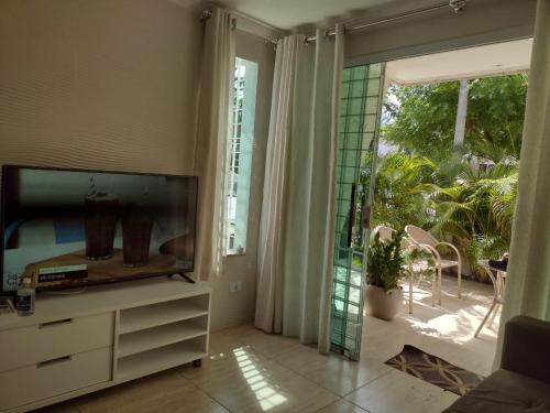 uma sala de estar com uma televisão e uma porta de vidro deslizante em Flat Beach Selma em Porto de Galinhas