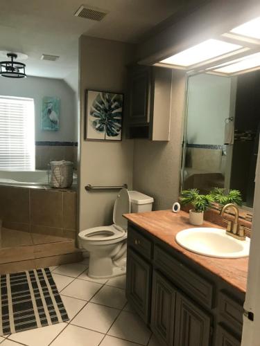 a bathroom with a sink and a toilet and a tub at Cheerful 4 bedroom home with pool and BBQ area with 5th bedroom option in Brownsville