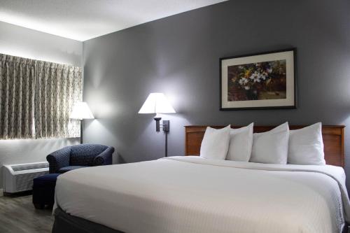 um quarto de hotel com uma cama grande e uma cadeira em New Victorian Inn - Sioux City em Sioux City