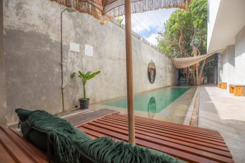 uma piscina com um guarda-sol e um banco em Turquoise Tulum Hotel em Tulum