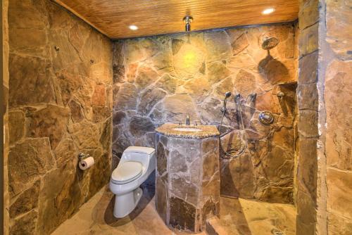 a stone bathroom with a toilet and a sink at Luxury Home with Pool on San Jacinto Riverfront! in Houston