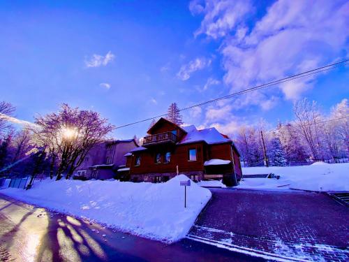 a house is covered in snow on a street at Leonardo Guesthouse in Świeradów-Zdrój