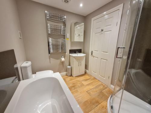 a bathroom with a tub and a toilet and a sink at Kimberley House in Whitby