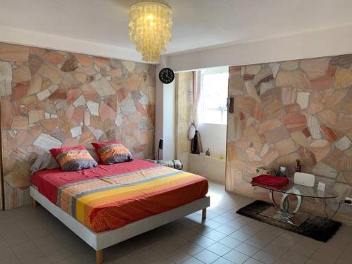 a bedroom with a bed and a stone wall at Omarina in Le Marin