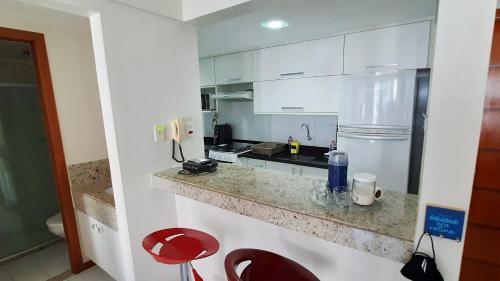 una cocina con armarios blancos y taburetes rojos en Apartamento completo Salvador, en Salvador