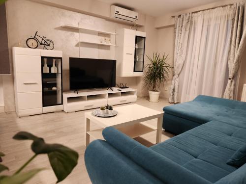 a living room with a blue couch and a tv at Airport Apartment Otopeni in Otopeni