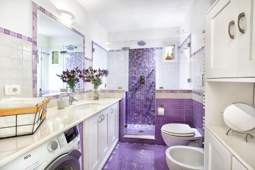 un bagno viola e bianco con servizi igienici e lavandino di AMORE RENTALS - Casa Paradisea a Positano