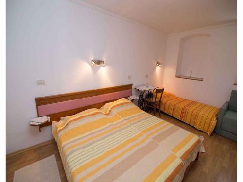 a bedroom with two beds and a table with a chair at Apartments in Veli Losinj 14928 in Veli Lošinj