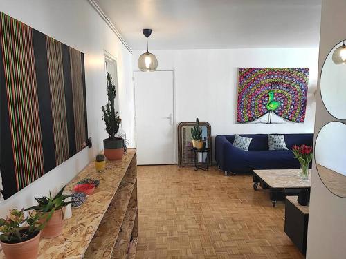 un salon avec un canapé bleu et des plantes dans l'établissement Appt d'artiste - 3 ch - Parking, à Rouen