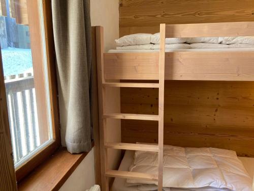 Etagenbett in einem Zimmer neben einem Fenster in der Unterkunft Ravissant 2 pièces rénové avec balcon, vue montagne, et accès skis aux pieds - FR-1-634-76 in Morzine