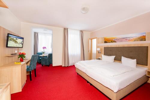 una habitación de hotel con una gran cama blanca y una alfombra roja en Hotel Garni Sonne, en Ahlbeck