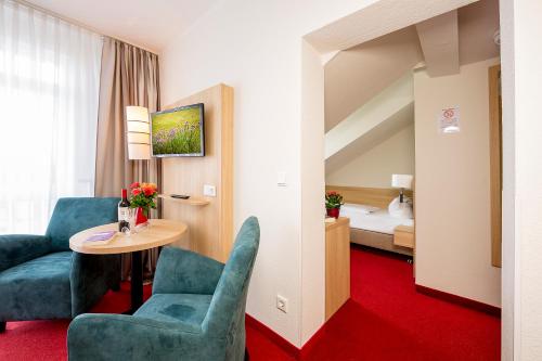 a hotel room with a table and chairs and a bed at Hotel Garni Sonne in Ahlbeck