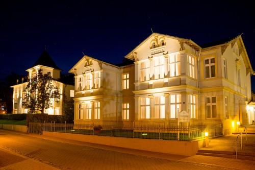 a large white building at night with lights at Hotel Garni Sonne in Ahlbeck