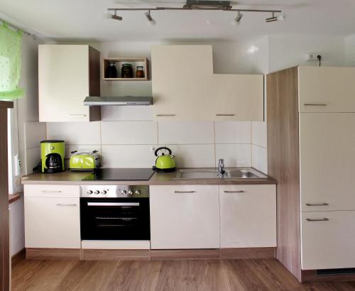 uma cozinha com armários brancos, um lavatório e um fogão em Villa LE em Leipzig