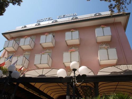 a pink building with windows and a sign on it at Hotel Vienna Ostenda e Ristorante il Danubio in Rimini