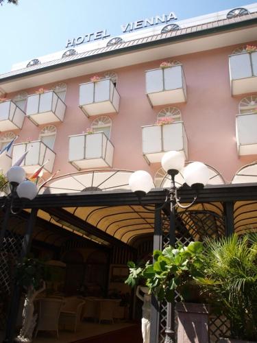 a pink building with white windows and a street light at Hotel Vienna Ostenda e Ristorante il Danubio in Rimini