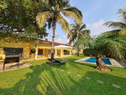 una casa con un patio con piscina y palmeras en Sompteuse villa avec piscine à 5 min de la plage en Pointe-Noire
