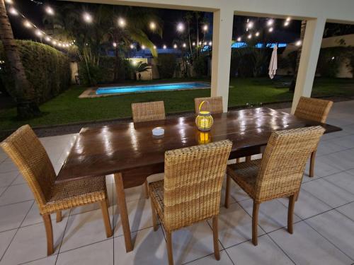 een houten tafel en stoelen op een patio in de nacht bij Sompteuse villa avec piscine à 5 min de la plage in Pointe-Noire
