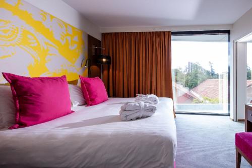 a bedroom with a large bed with pink pillows at Crowne Plaza Montpellier Corum, an IHG Hotel in Montpellier