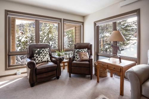 a living room with two chairs and a table and windows at Steps to Ski Lifts - Condo with Walk-Out Patio! in Big Sky