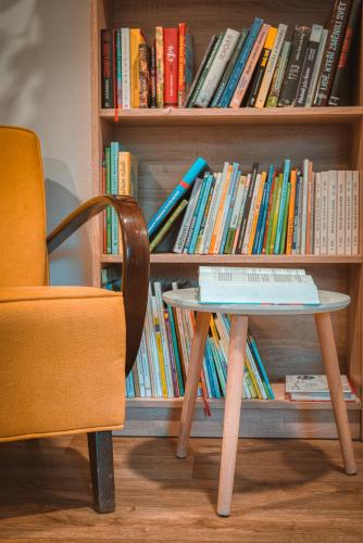 a table next to a book shelf with books at Penzion Medové údolí in Čábuze