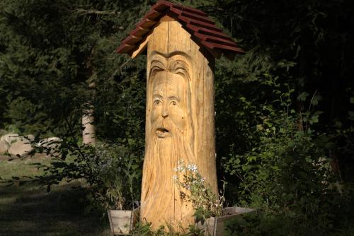 a wooden post with a face on top of it at Penzion Medové údolí in Čábuze