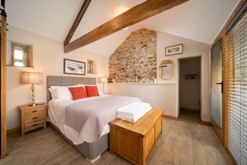 um quarto com uma cama e uma parede de tijolos em The Hen House at Accott Manor 