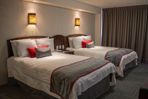 Habitación de hotel con 2 camas con almohadas rojas en Ramada Plaza by Wyndham Leon en León