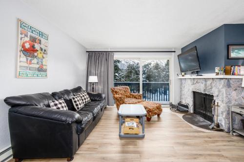 a living room with a black leather couch and a fireplace at Cozy Crystal Mountain Condo in Girdwood