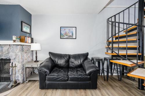 a black leather couch in a living room with a fireplace at Cozy Crystal Mountain Condo in Girdwood