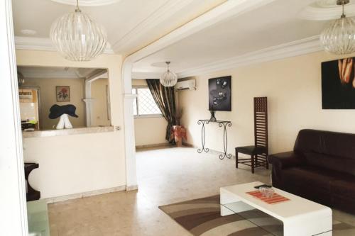 ein Wohnzimmer mit einem Sofa und einem Tisch in der Unterkunft Villa de charme avec jardin à Makepe in Douala