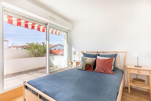 ein Schlafzimmer mit einem Bett und einem großen Fenster in der Unterkunft Balkoia superbe appartement de 75 m2 entièrement rénové in Saint-Jean-de-Luz