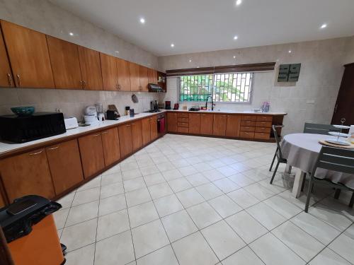 a large kitchen with wooden cabinets and a table at Sompteuse villa avec piscine à 5 min de la plage in Pointe-Noire