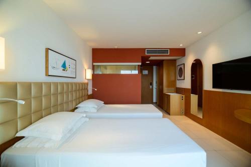 a hotel room with two beds and a flat screen tv at Hotel Luzeiros São Luis in São Luís