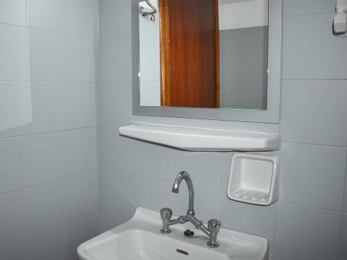 a white bathroom with a sink and a mirror at Ελαία Apartments in Edipsos