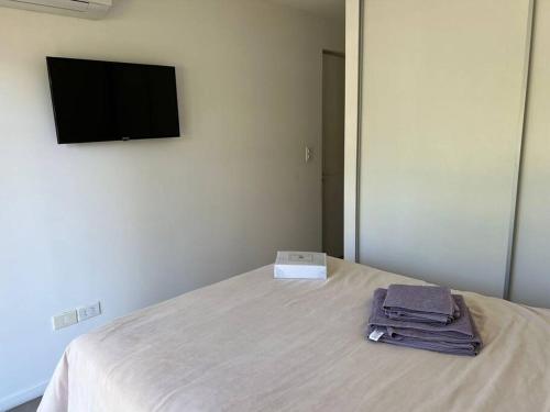 1 dormitorio con 1 cama, TV y toallas en Cozy nice apartment, en Punta del Este