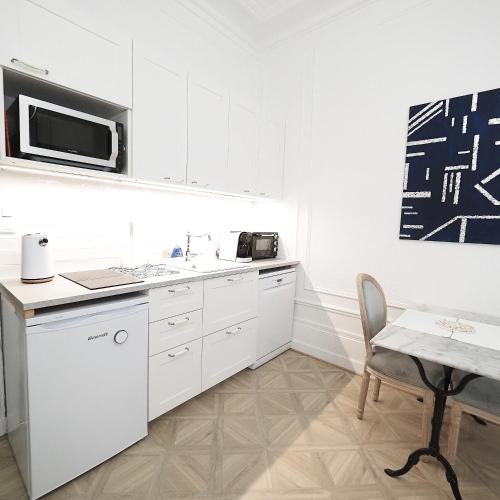 une cuisine blanche avec un évier et un micro-ondes dans l'établissement LE PALAIS DES PARCS - Chic - Centre Ville - Face au Parc, à Vichy