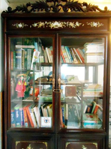 a wooden book cabinet filled with books at North Hostel N.2 in Hanoi