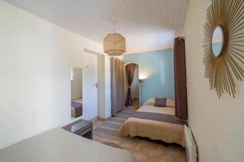 1 dormitorio con 2 camas y espejo en la pared en Gîtes Le Bois Berranger en Saint-Urbain