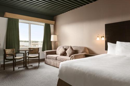 Travelodge by Wyndham Baie Comeau في بيه كومو: غرفة في الفندق بها سرير وأريكة ومكتب