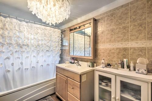 a bathroom with a sink and a tub and a chandelier at Cute East Hampton Cottage with Patio - Walk to Beach in East Hampton