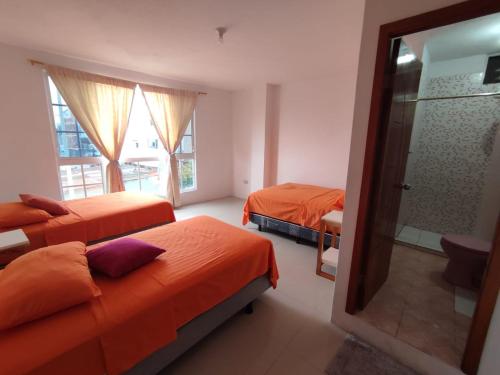 1 dormitorio con 2 camas con sábanas de color naranja y espejo en PELICAN TOURS, en Puerto Baquerizo Moreno
