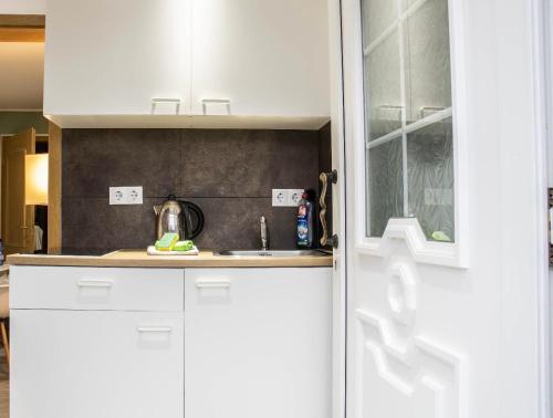 a kitchen with white cabinets and a sink at Kleine gemütliche Einliegerwohnung mit Garten und Pool in Nordstemmen