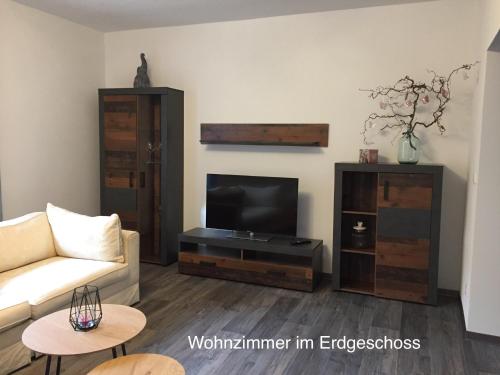ein Wohnzimmer mit einem Sofa und einem Flachbild-TV in der Unterkunft FEWO am Wald in Krauschwitz