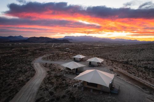 Camp Elena - Luxury Tents Minutes from Big Bend and Restaurants في تيرلينغوا: منظر جوي للخيام في الصحراء عند غروب الشمس