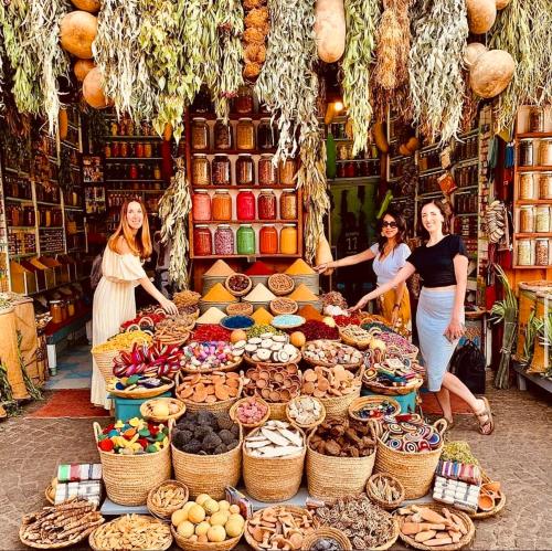 three women standing in a market with a table of food at Riad Allal in Marrakech