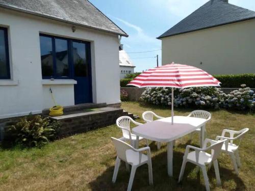 a table and chairs with an umbrella in a yard at Port Manec'h - Maison vue mer à deux pas du GR34 in Névez